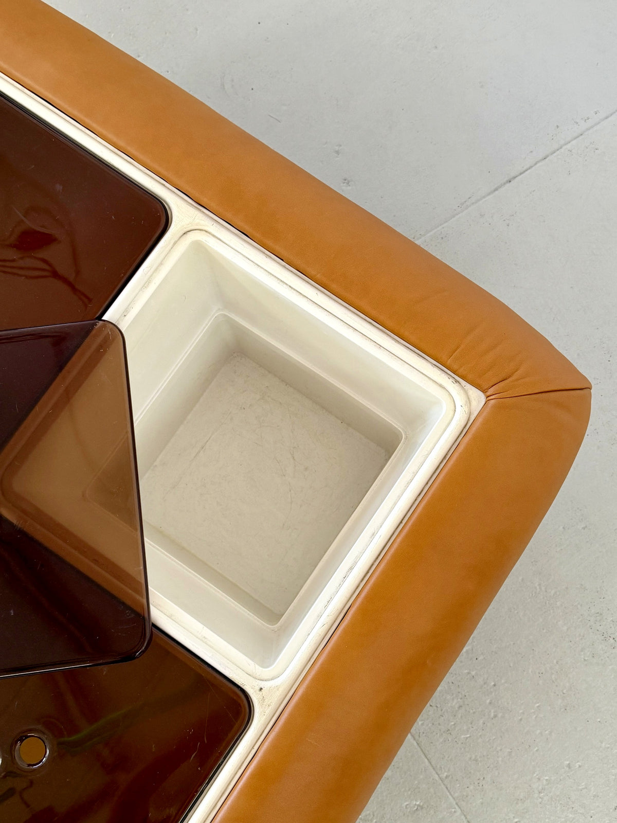 Corner detail of tan leather Nuvolone coffee table showing storage compartment edge